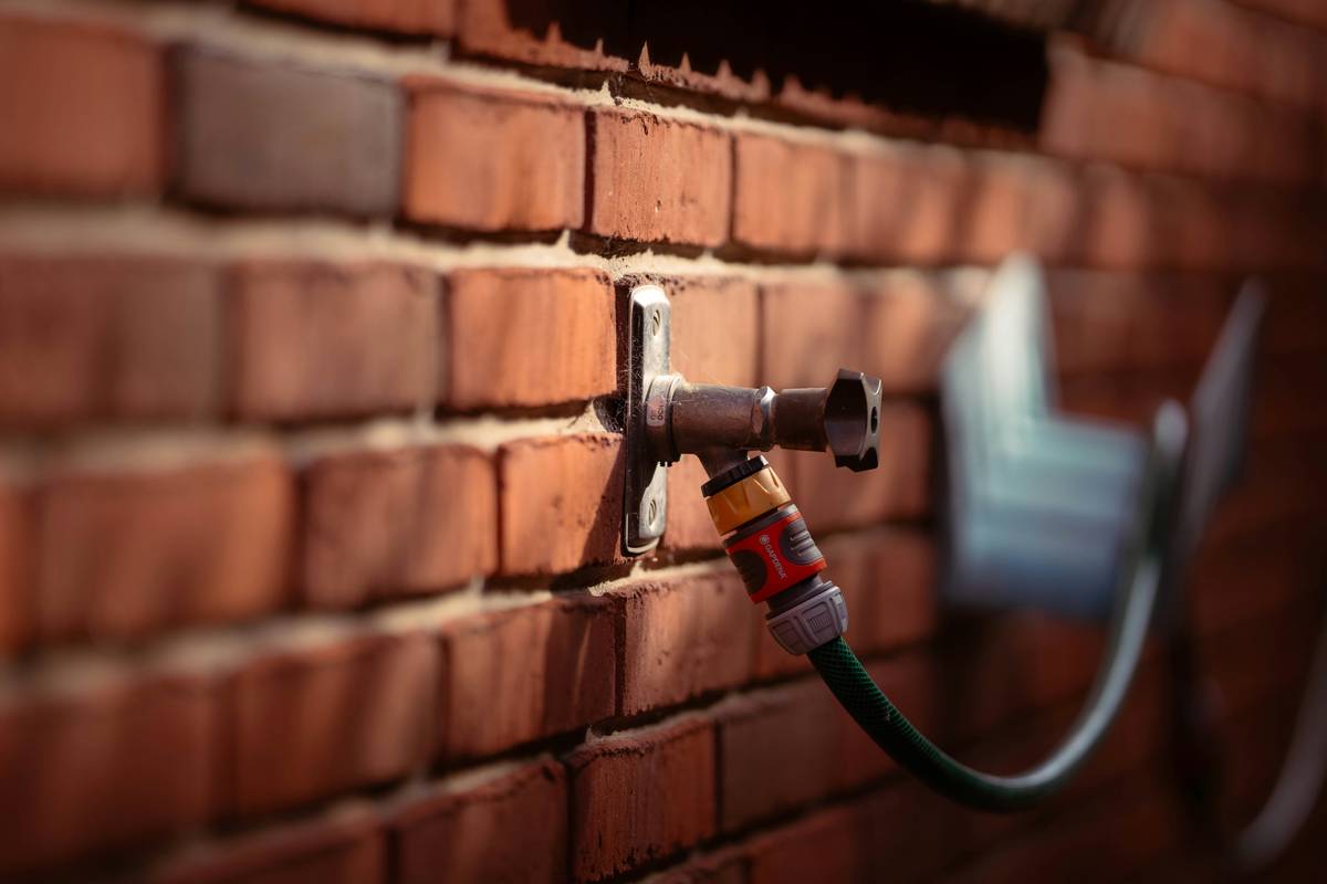 Close-up of adjustable spray nozzle brass attached to a garden hose, showing mist-to-jet dial and solid metal construction